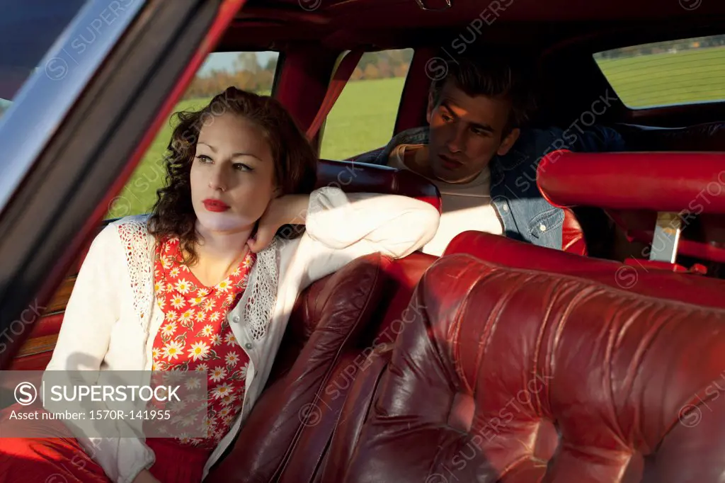 A rockabilly woman and man sitting in a vintage car