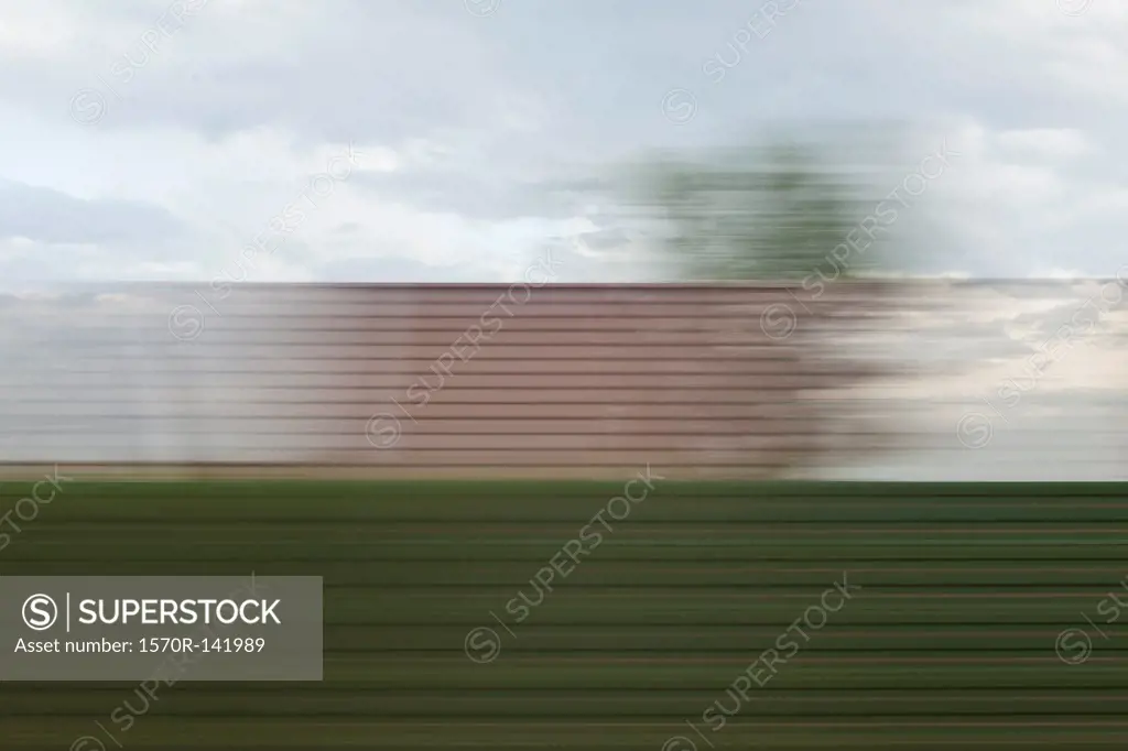 A building and sky in blurred abstract pattern seen from moving train