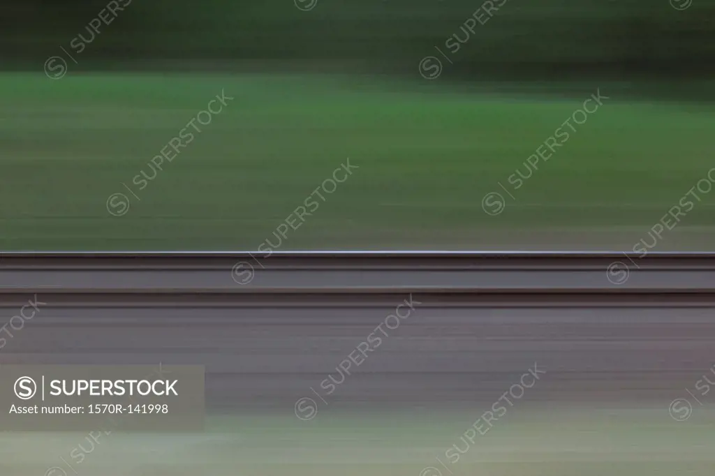 Railroad tracks and grass seen in blurred abstract pattern from moving train