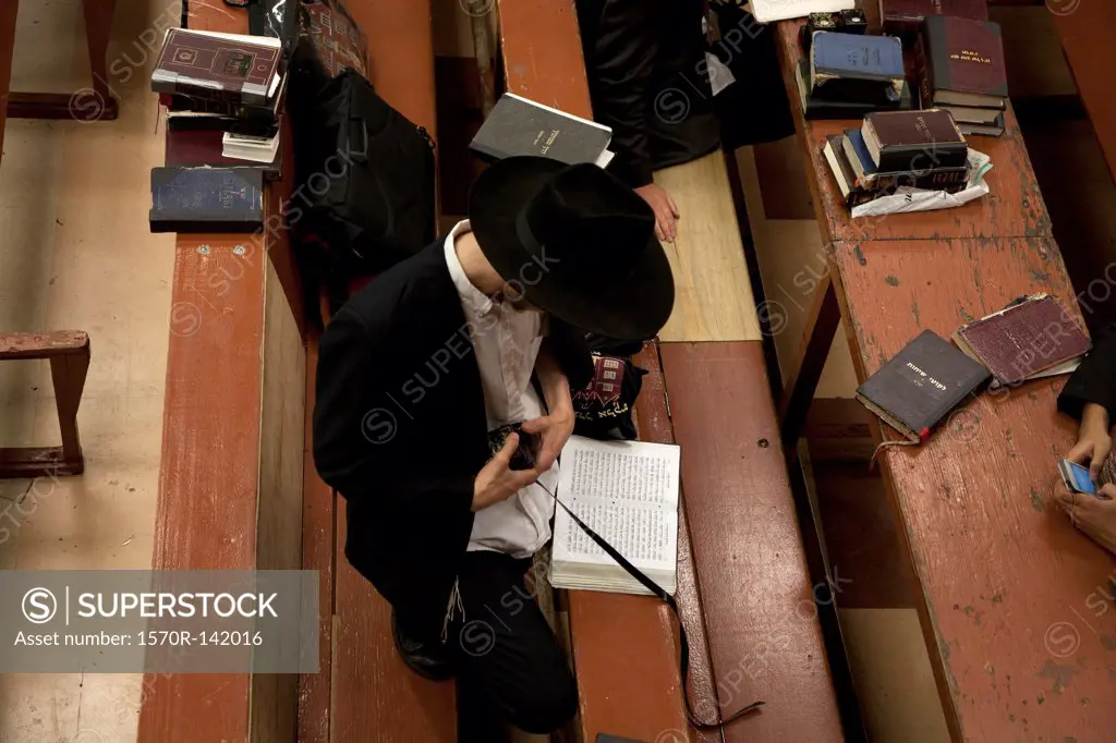 Jewish man holding tefillin  in synagogue