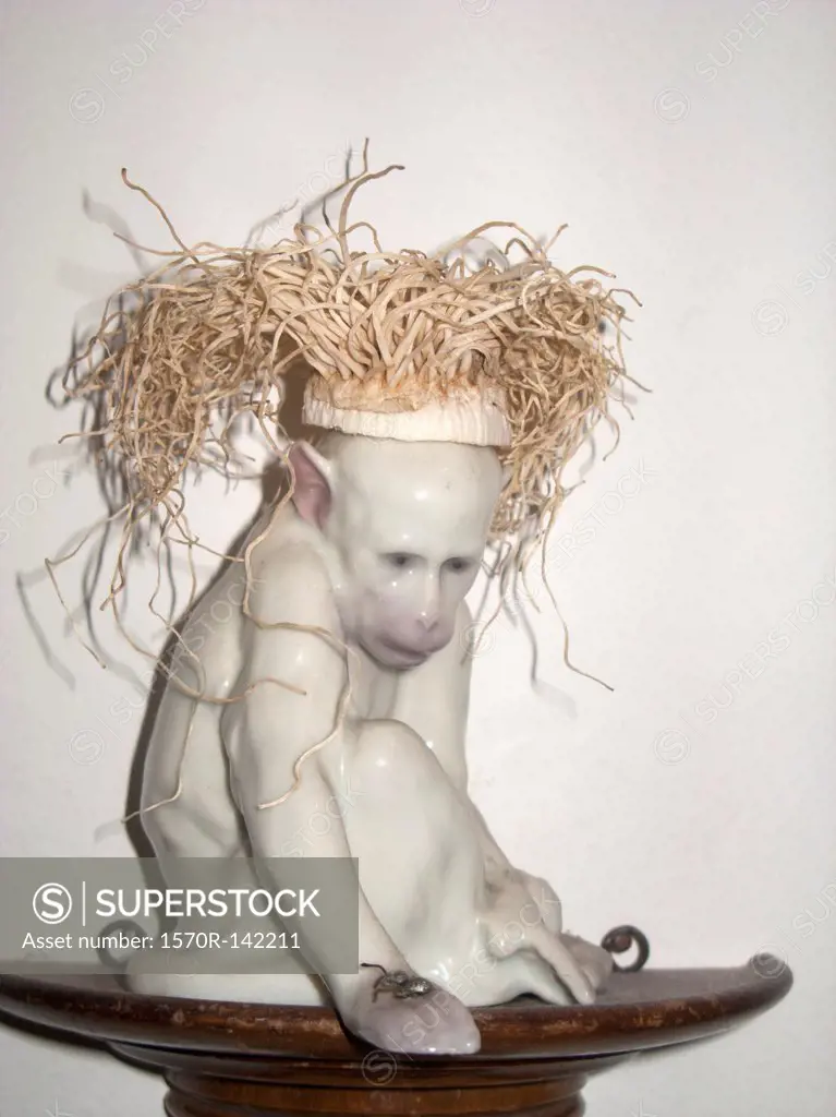 A ceramic monkey with straw hair