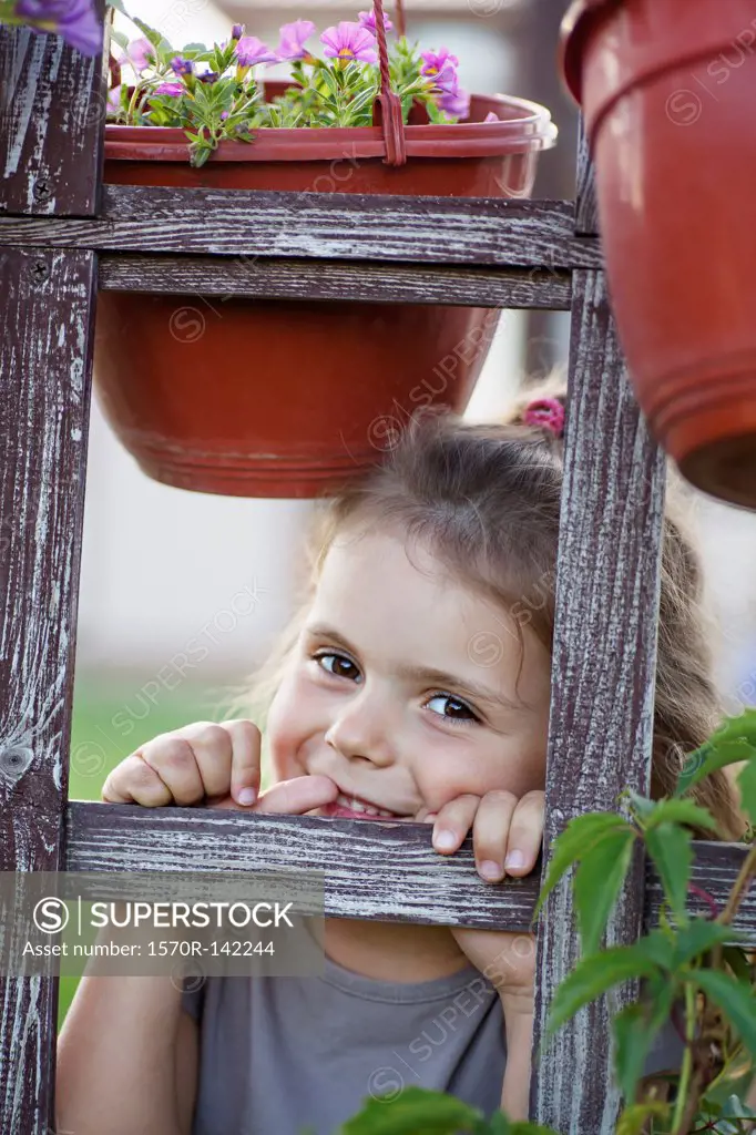A young smiling girl looking through a trellis