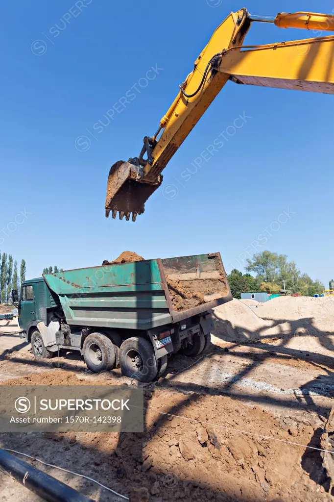 Digger loading soil onto dumper truck