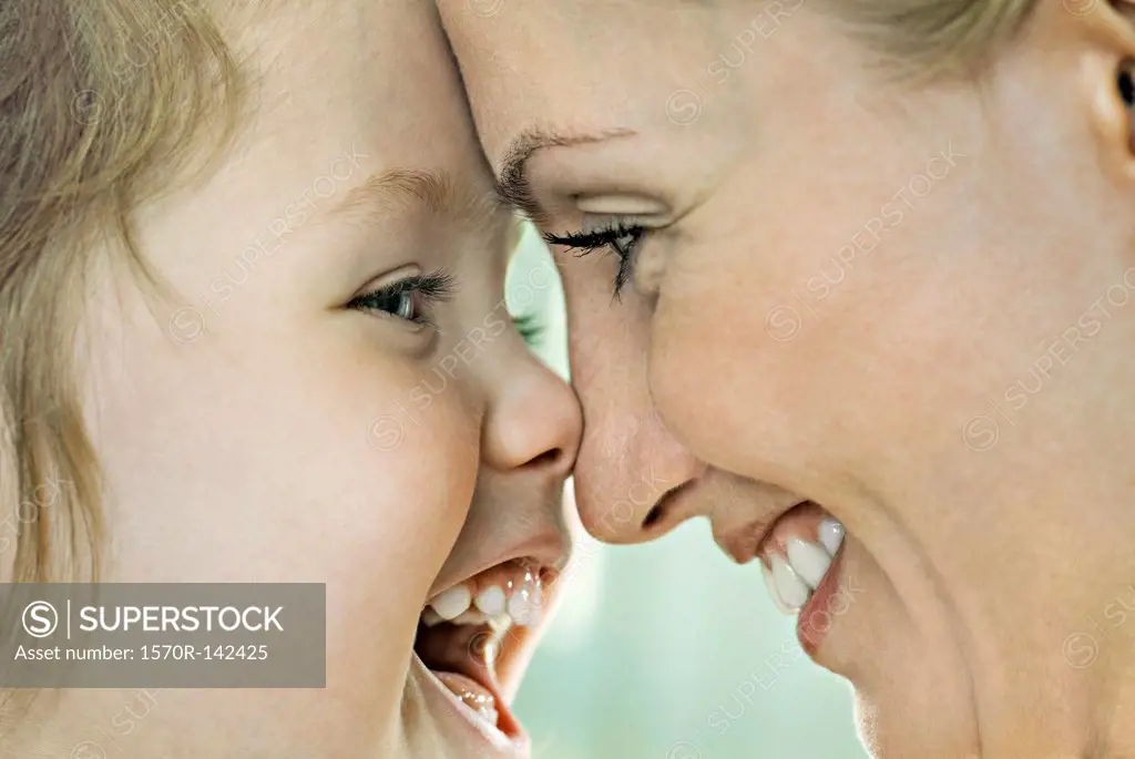 A laughing girl touching noses with her smiling mother, close-up