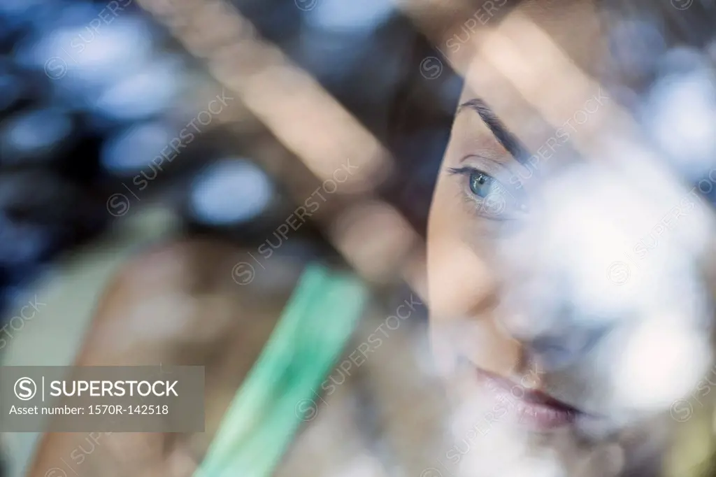A young woman looking thoughtfully out the window of a stationary car