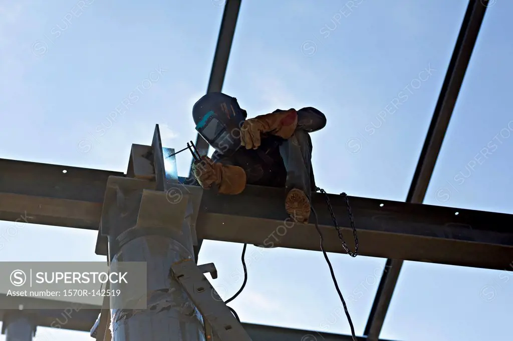 A welder welding steel on a high beam