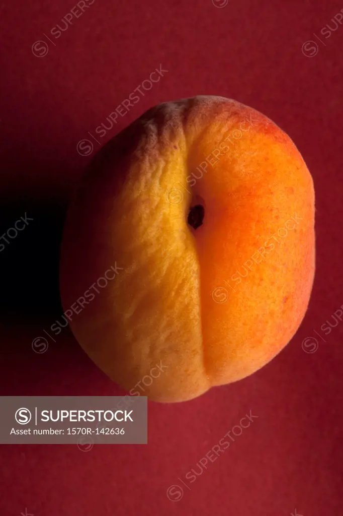 A slightly wrinkled peach on a red background