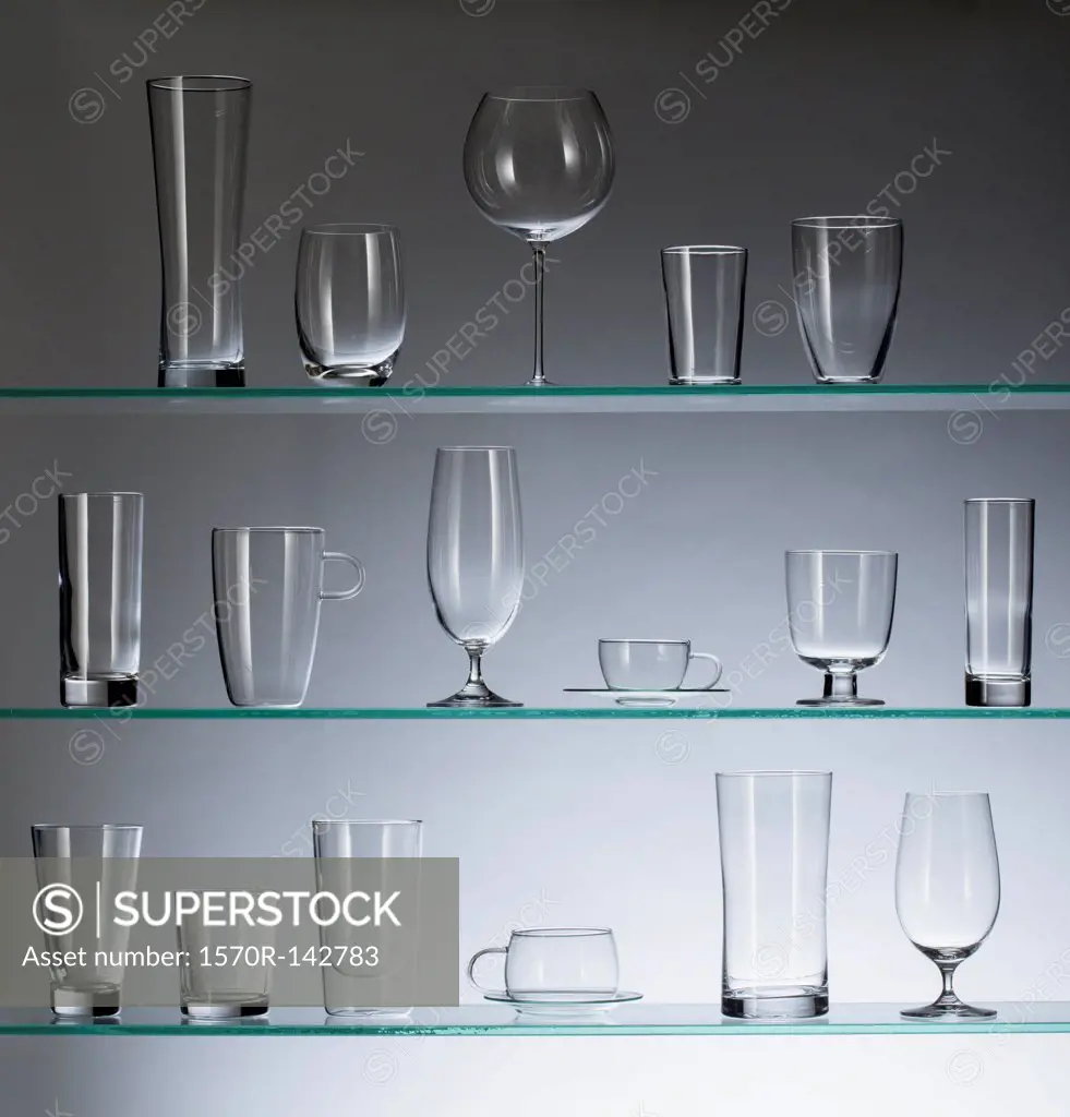 A collection of various types of drinking glasses arranged neatly on three shelves