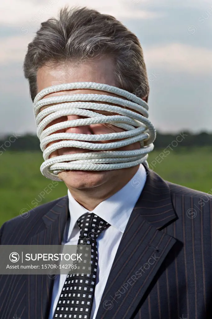 A mature businessman with rope wrapped around his face