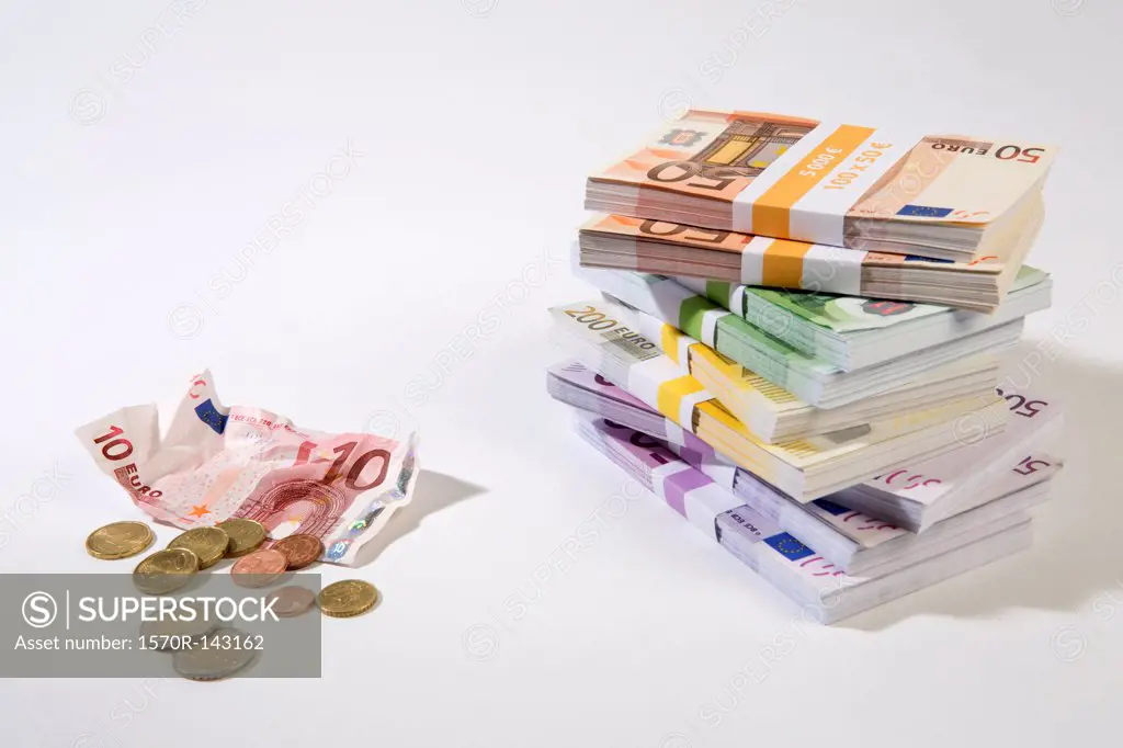 Stack of large billed Euro banknotes next to a crumpled ten note and change