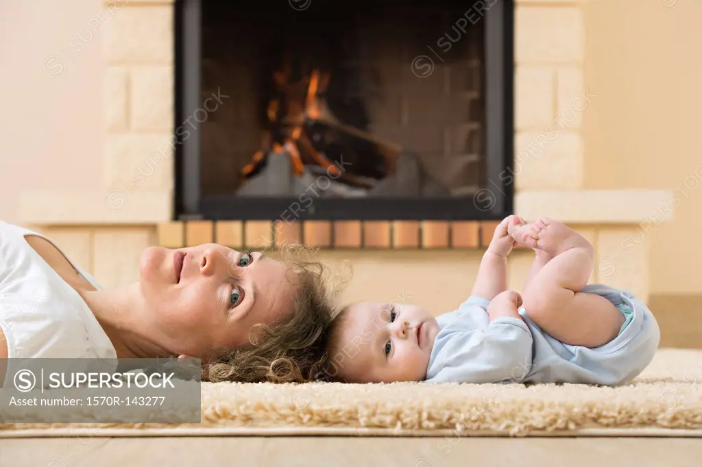 Mother and daughter lying head to head on carpet in front of fire