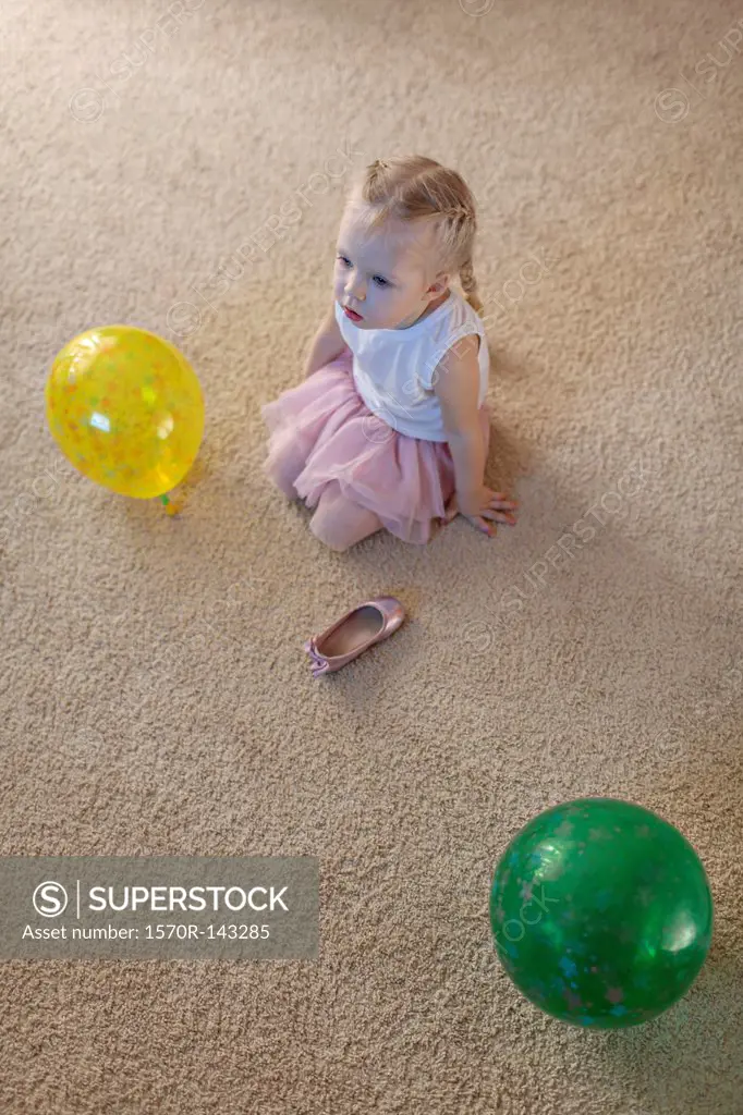 Little girl between two balloons as her ballet shoe lies on the floor