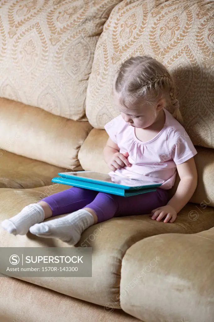 Girl using digital tablet on sofa