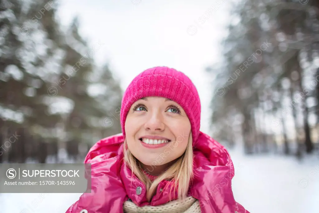 A beautiful woman in a knit cap looking up, outdoors in winter