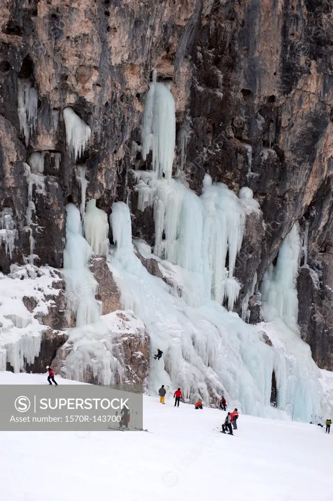Skiers observe ice climber on rock face at Lagazuoi, South Tyrol, Italy