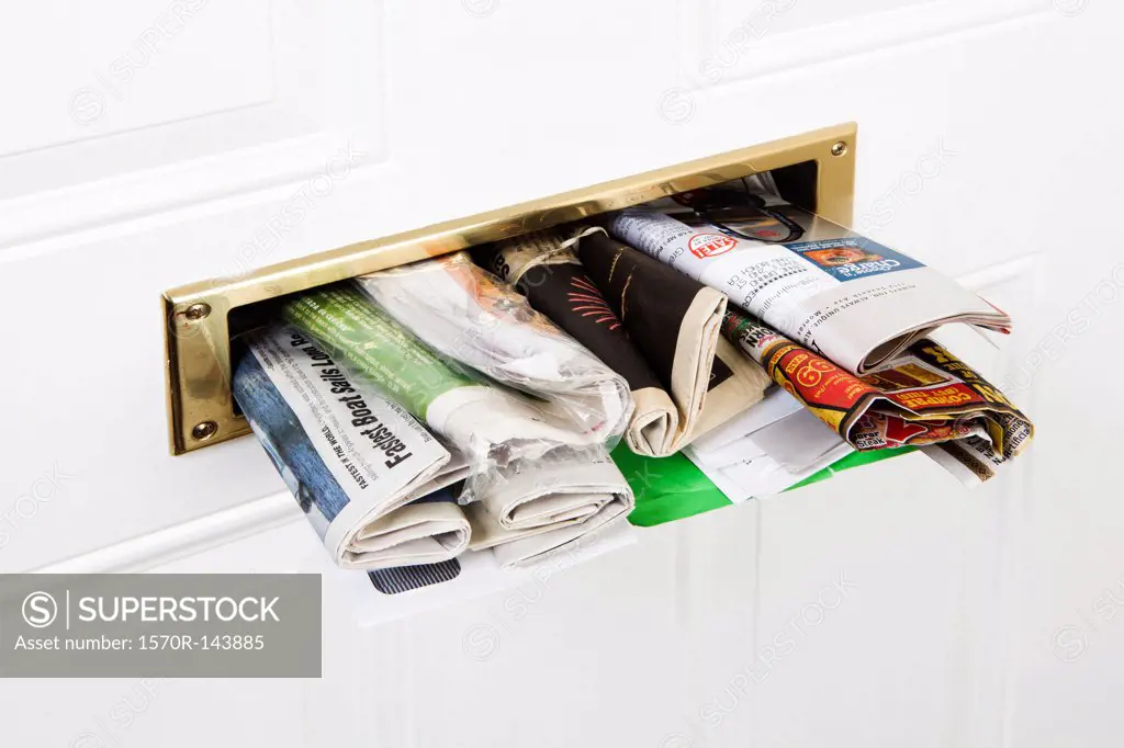 A mail slot stuffed with mail and newspapers, close-up