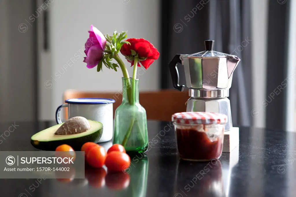 A table with espresso maker, coffee cup and ingredients for breakfast