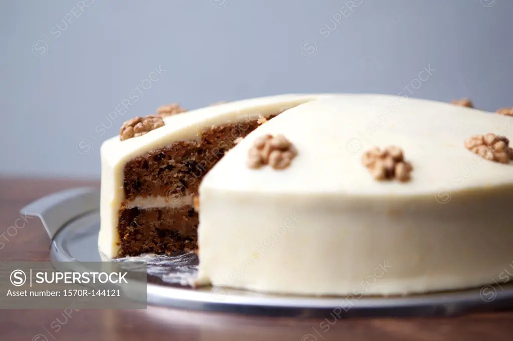 A carrot cake with a slice missing for sale in a cafe