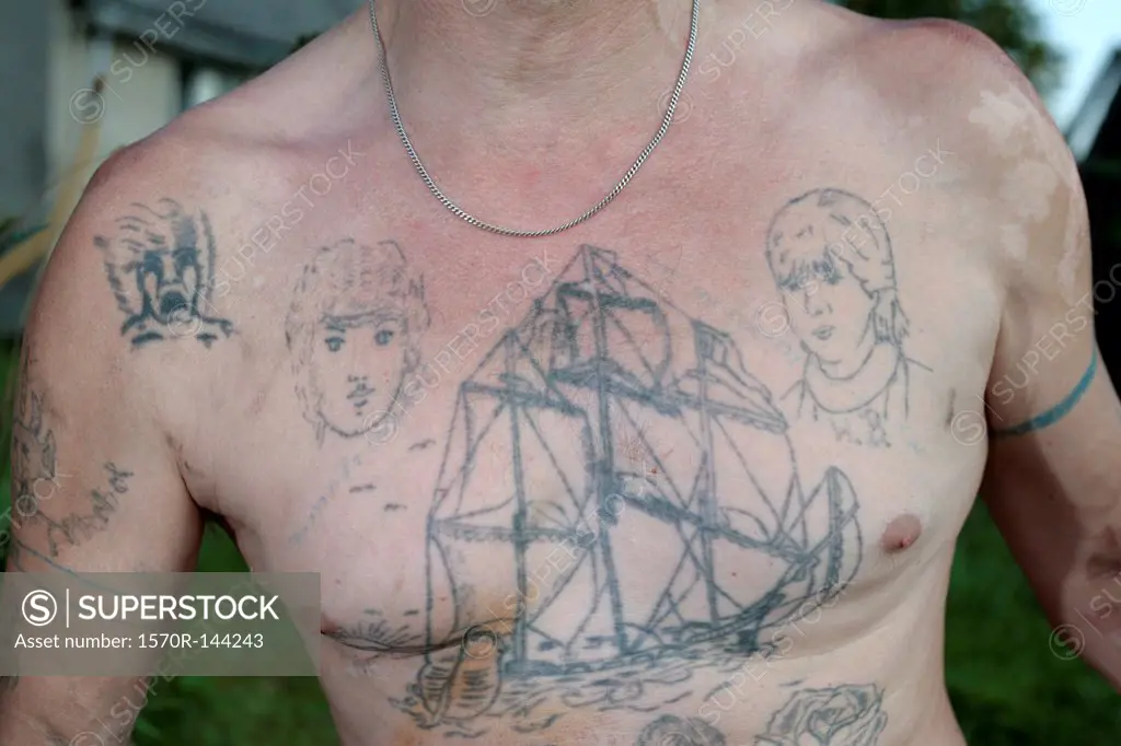 A mature man's chest with faded tattoos