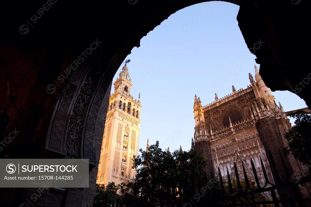 Exterior view of Seville Cathedral, including La Giralda from a darkened archway