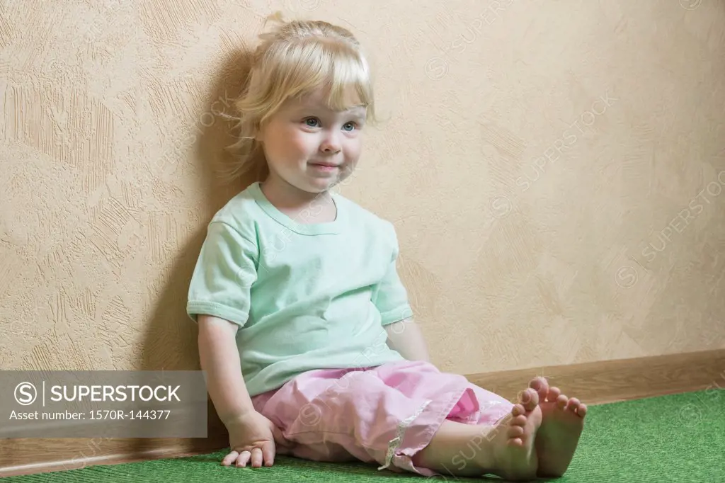 Smiling girl sitting against wall