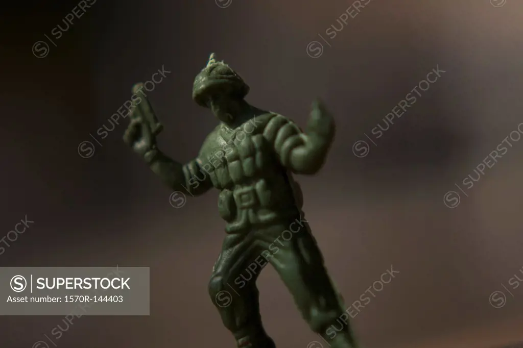 A toy solider holding a gun with arms raised up in surrender