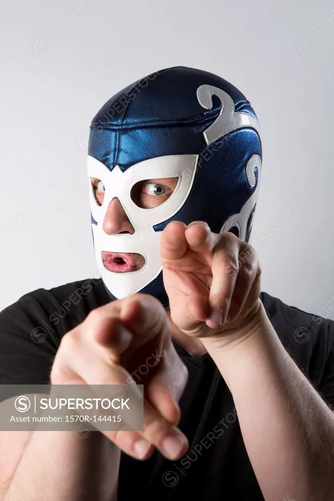 A man wearing a Lucha Libre wrestling mask and gesturing bizarrely with his hands