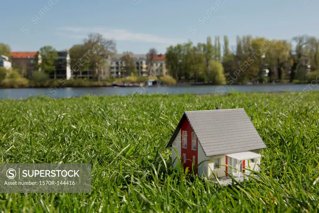 A miniature house on the lawn near the shore of a river