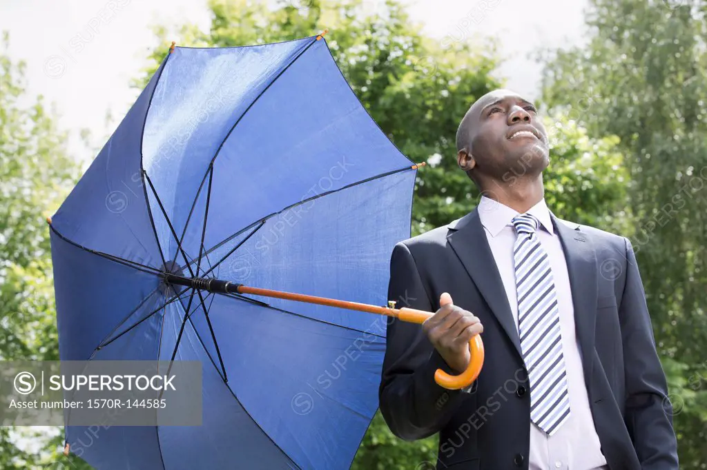 Businessman holding umbrella realising the rain has stopped