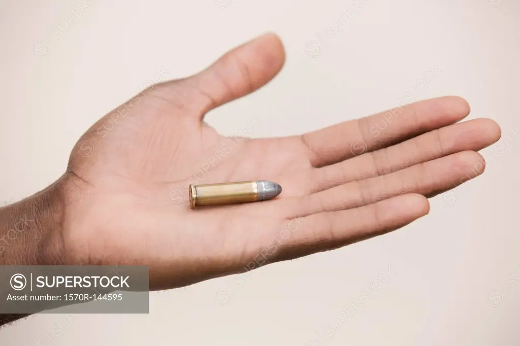 Man holding out a single bullet