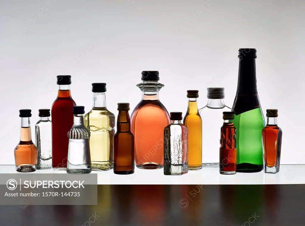 A grouping of various miniature bottles of alcohol without labels, back lit