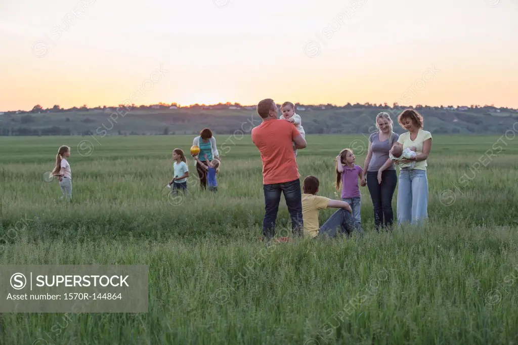 Families relaxing in a field in a rural setting