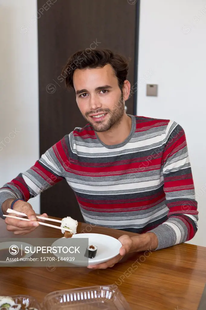 Man holding chopsticks and sushi, portrait