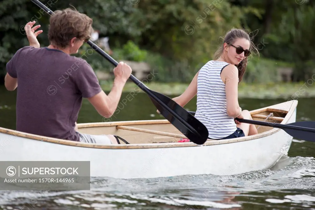 Young couple rowing canoe on lake