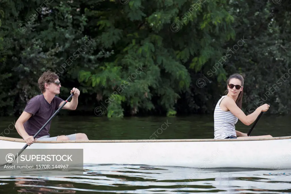 Young couple rowing canoe on lake
