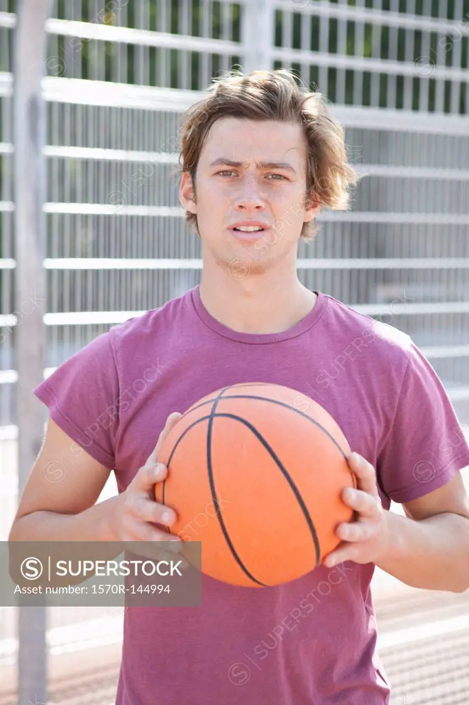 Mid adult man holding basketball, portrait