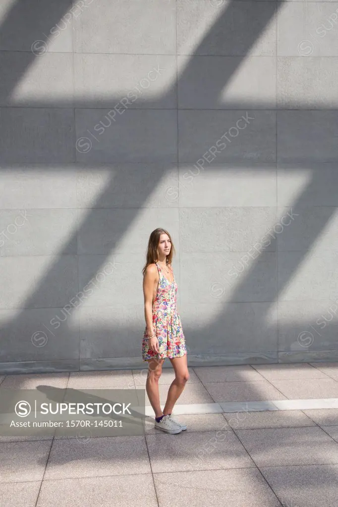 Young woman standing on pavement, looking away