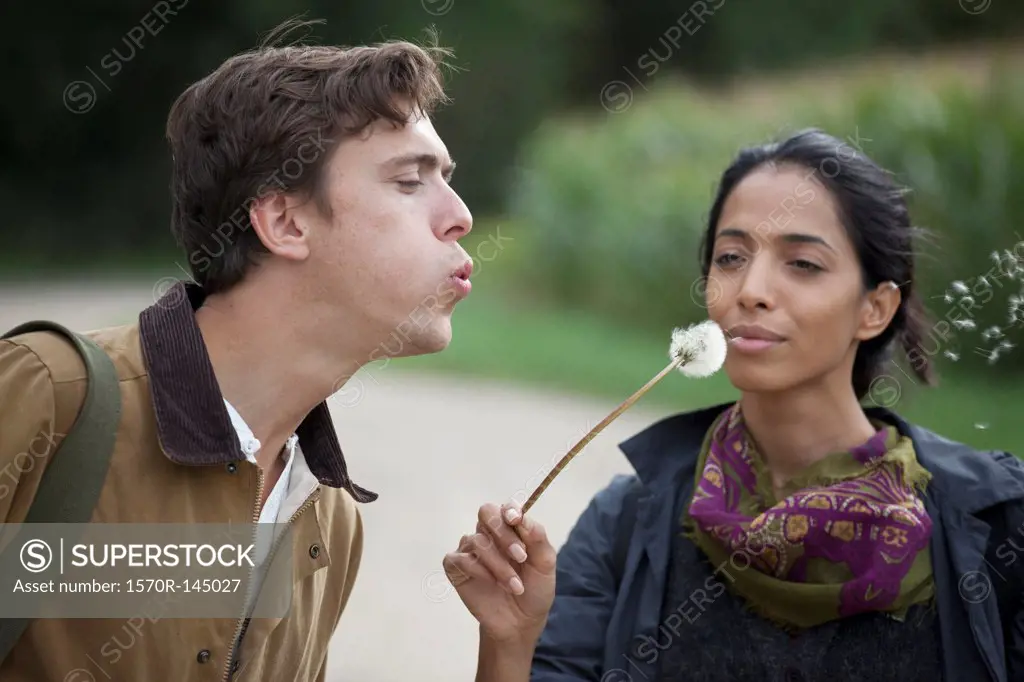 Couple blowing dandelion and making wish