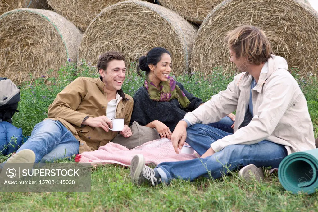 Men and woman resting in field and having drink