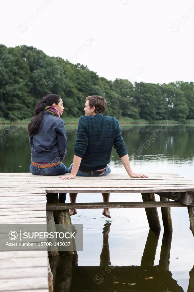 Young couple sitting on wooden pier