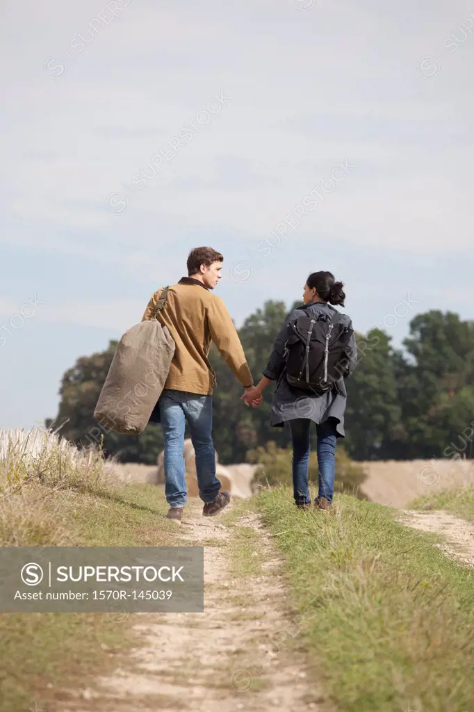 Young couple holding hands and walking through dirt track