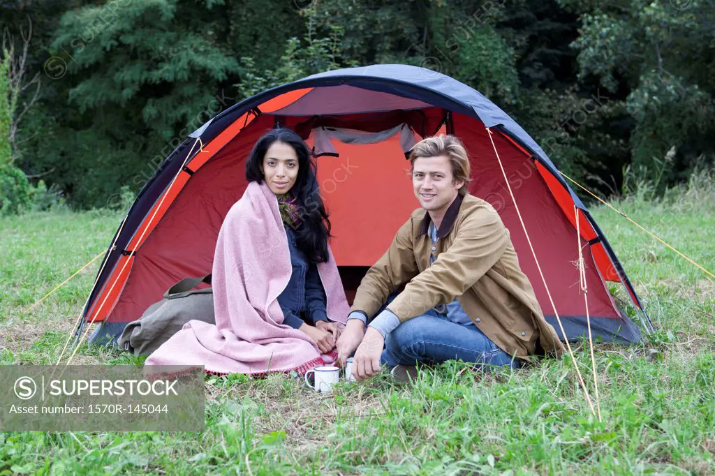 Young couple sitting near dome tent, portrait