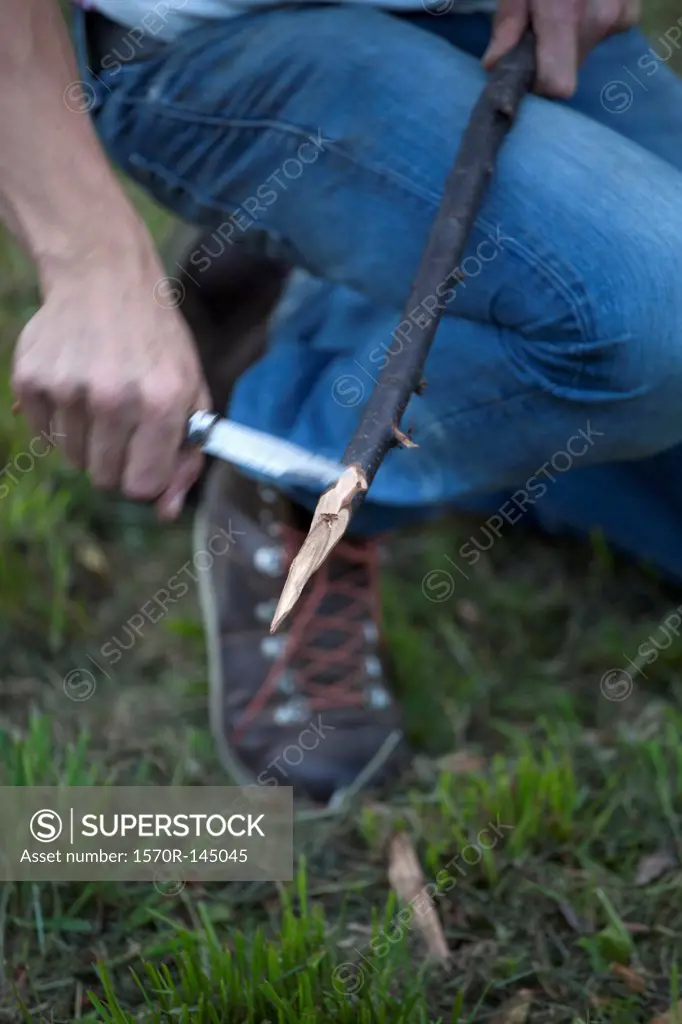 Man cutting stick with knife, close-up