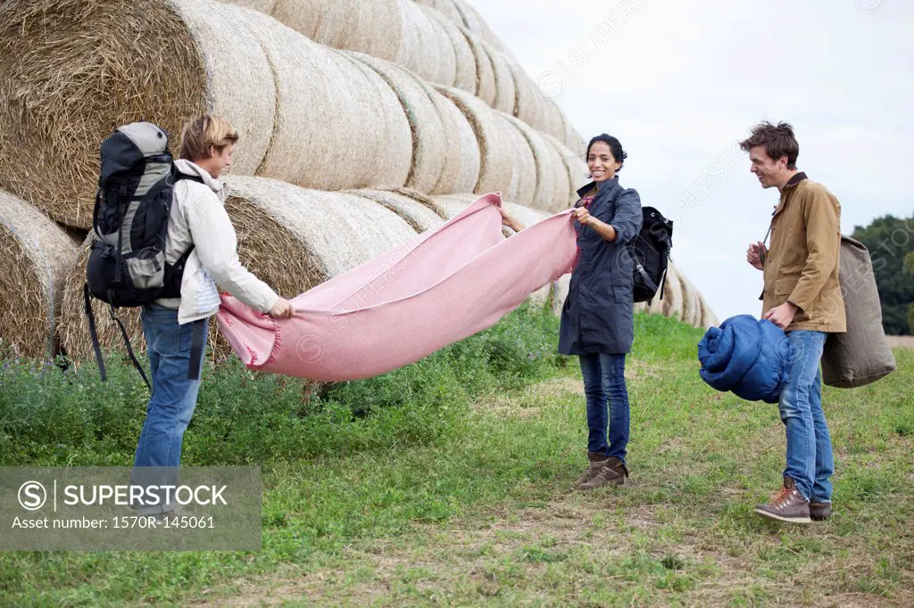 Men and woman with camping accessories standing in field
