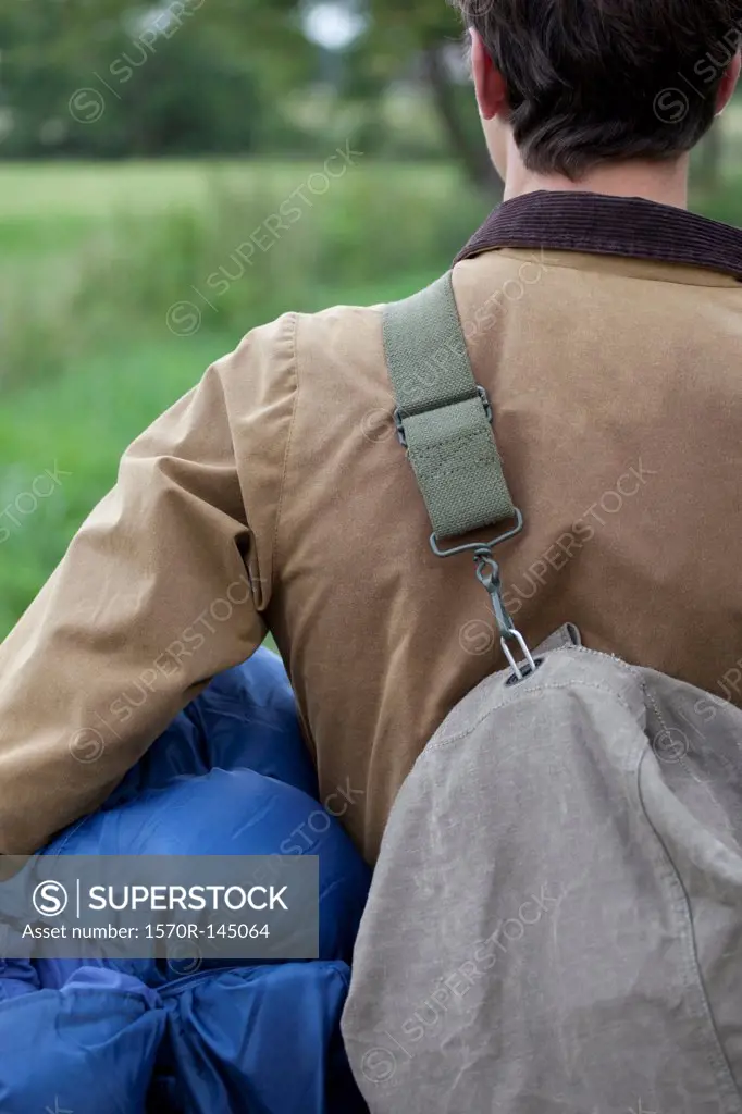 Man carrying sleeping bag and rucksack, close-up