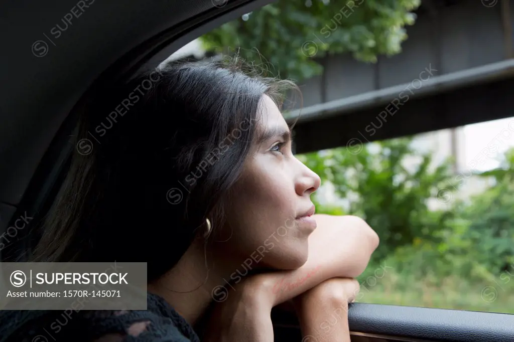 Woman sitting in car and looking through window, close-up