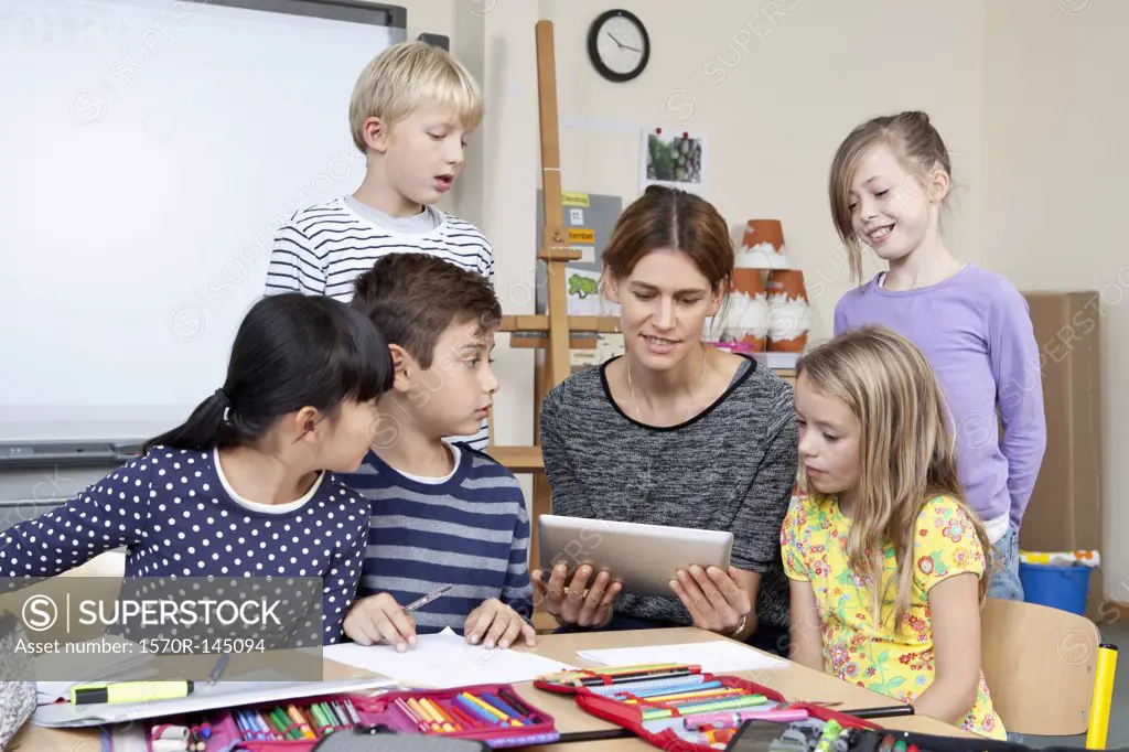 Teacher using digital tablet with students in classroom