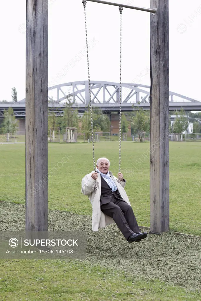Senior man sitting on swing in park