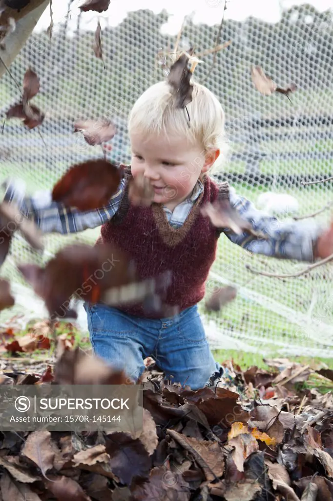 Baby boy throwing dry leaves