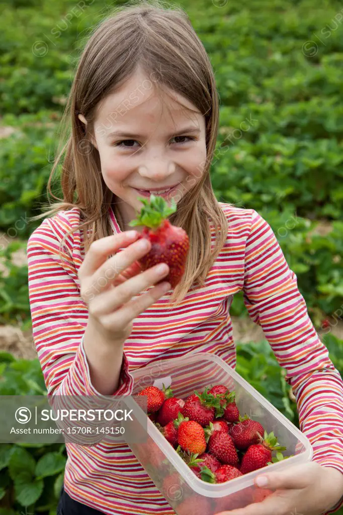 Portrait of girl holding strawberry box, smiling